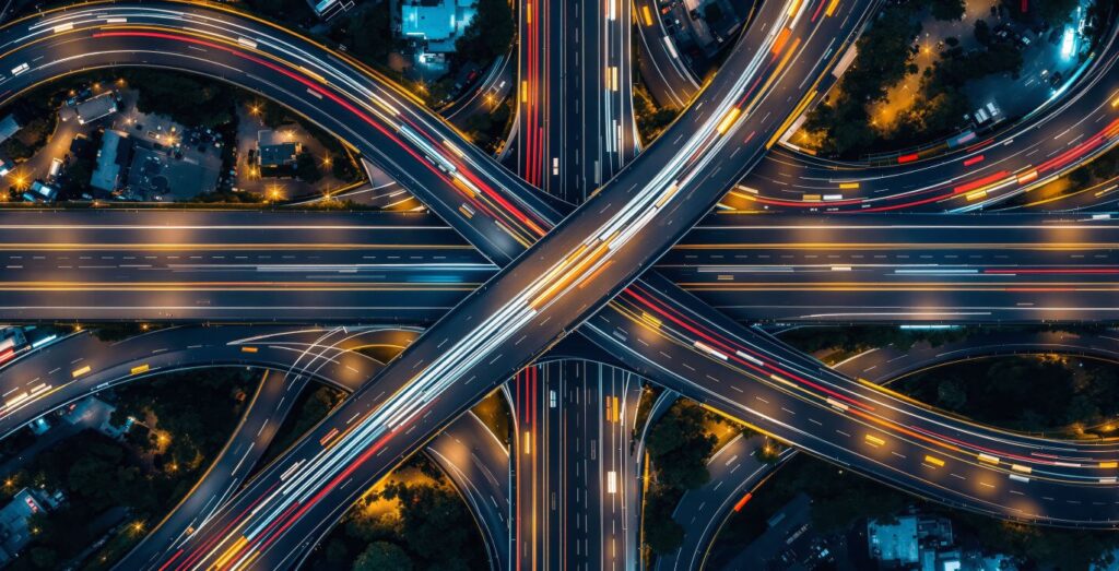 Luftaufnahme eines leuchtenden Autobahnkreuzes bei Nacht als Symbol für WAN Lösungen und die sichere Verbindung von Unternehmensstandorten