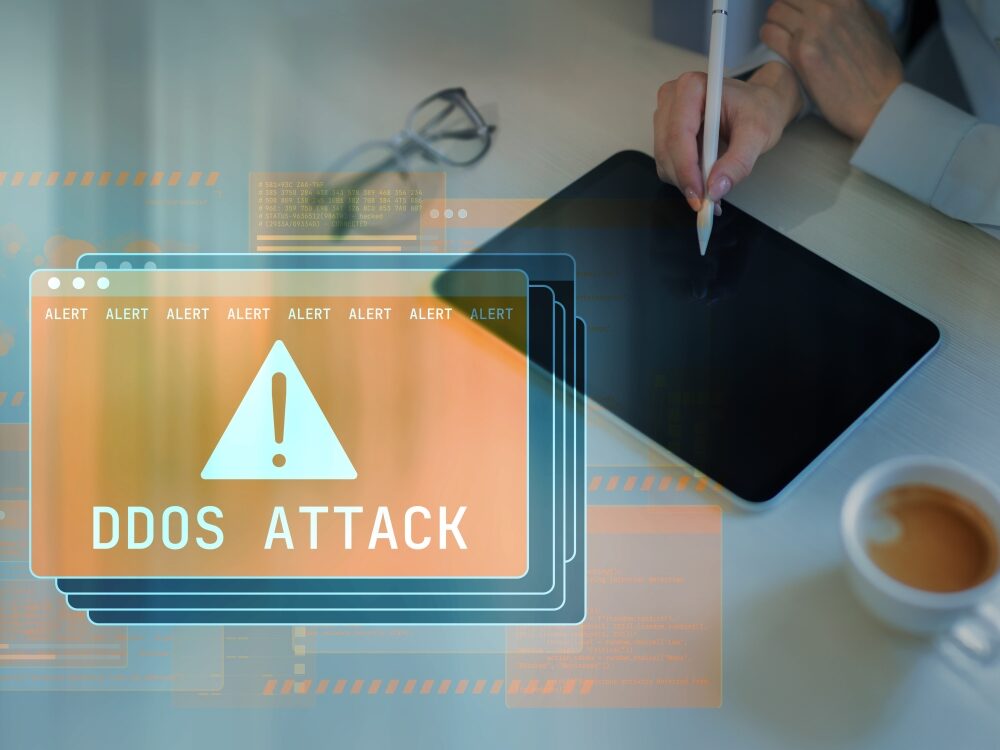 Warnhinweis „DDoS Attack“ auf mehreren digitalen Monitoren – Symbolbild für Cyberangriffe und Schutzmaßnahmen gegen DDoS-Attacken.